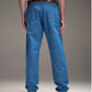 Vista traseira de calça jeans azul Aporo Sulco com bolsos quadrados bordados e cinto marrom, usada por modelo com camiseta branca e botas pretas