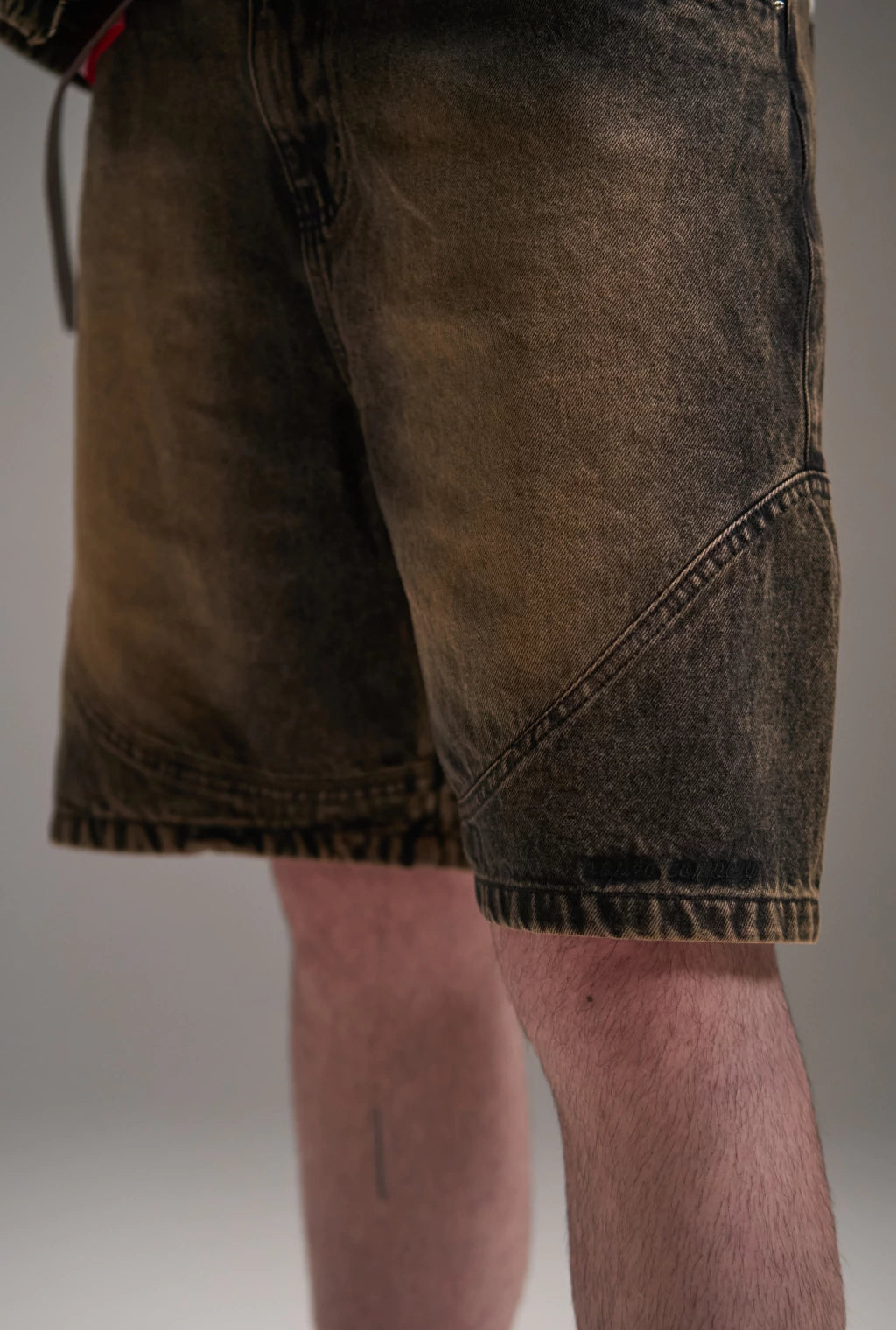 Bermuda Aporo Terra em tecido jeans com lavagem escura, vista parcial das pernas de um homem