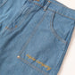 Detalhe da Calça Aporo Sulco em tecido jeans azul claro com costura laranja e bordado "aporo company" no bolso lateral