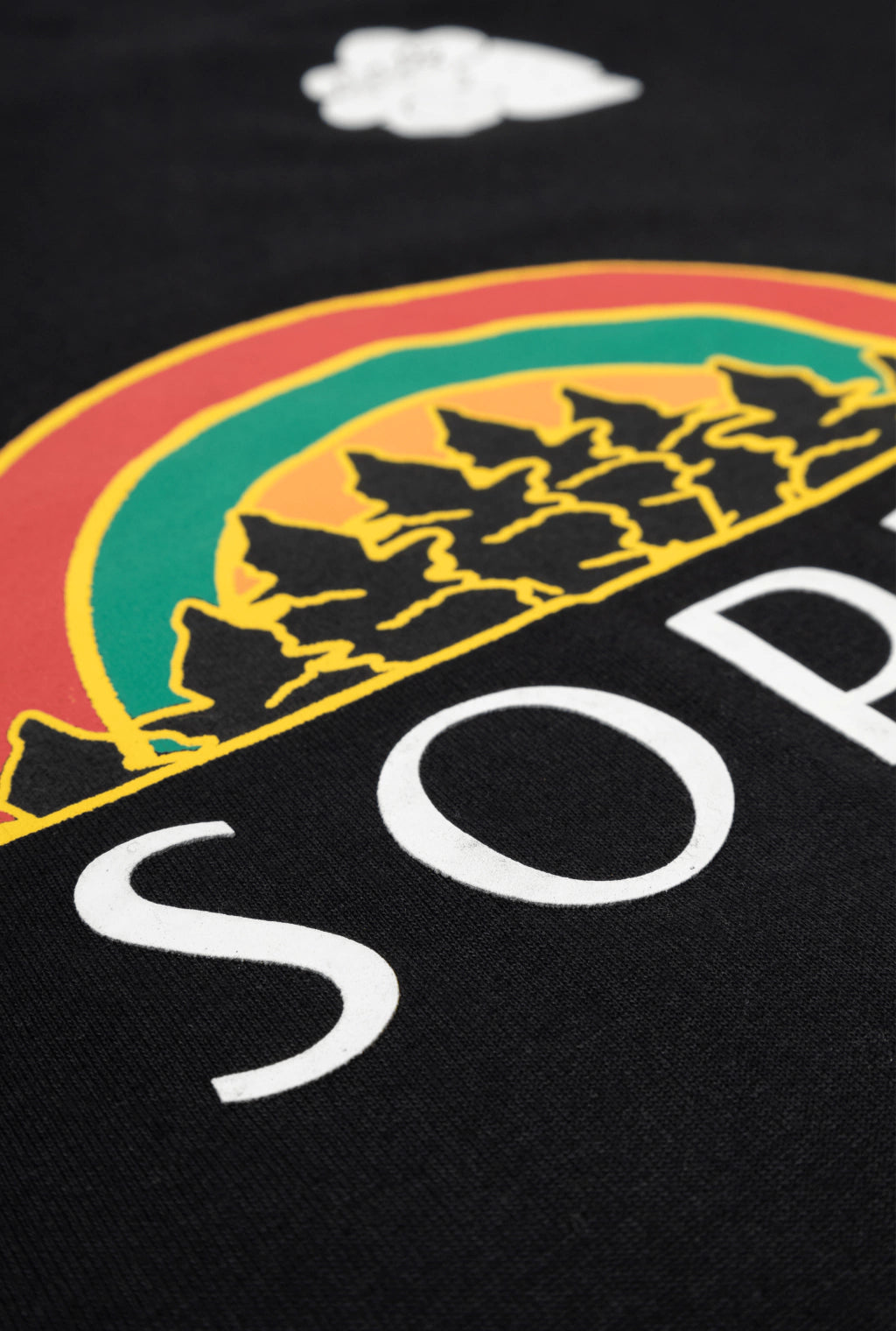 Camiseta preta Rolimã Racing com estampa colorida de arco-íris e logo da marca SOPRO.
