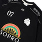 Camiseta preta Rolimã Racing com estampa colorida de arco-íris e logo da marca SOPRO.