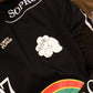 Camiseta preta Rolimã Racing com estampa colorida de arco-íris e logo da marca SOPRO.