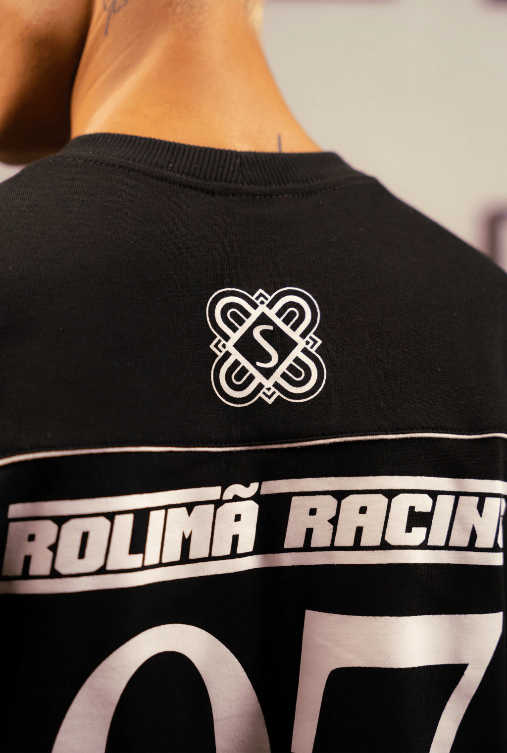 Camiseta preta Rolimã Racing com estampa colorida de arco-íris e logo da marca SOPRO.